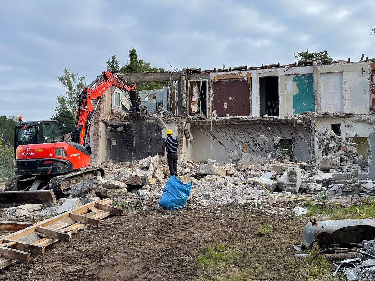 Abbrucharbeiten an einem Haus mit Bagger im Vordergrund